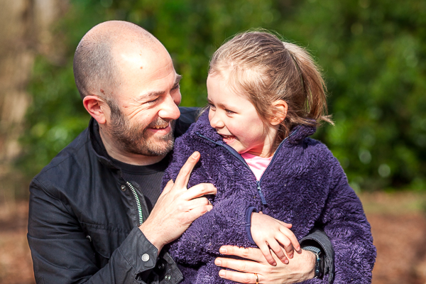 ather holding his daughter outdoors, both smiling and looking at each other in natural light in Fleet Hamoshire
