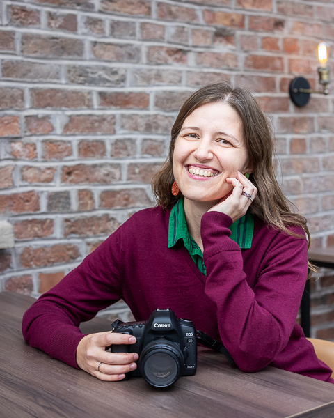 Branding portrait of Hampshire photographer holding a camera while sitting at a café table
