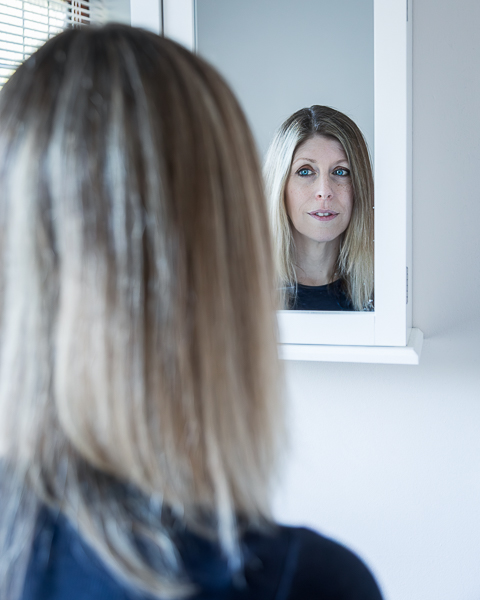 Reflective branding portrait of coach Jo Allen looking into a mirror during a personal branding session in Hampshire