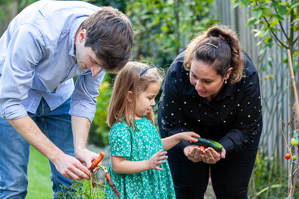 Family harvesting vegetables together in the garden during a natural family photography session in Hampshire