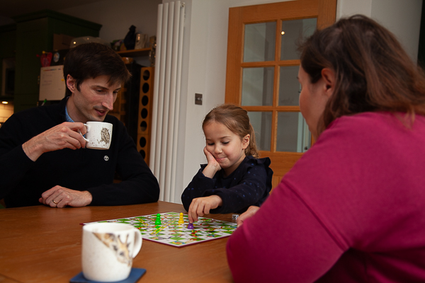 Family playing a board game together at home during a relaxed indoor family photoshoot in Fleet, Hampshire